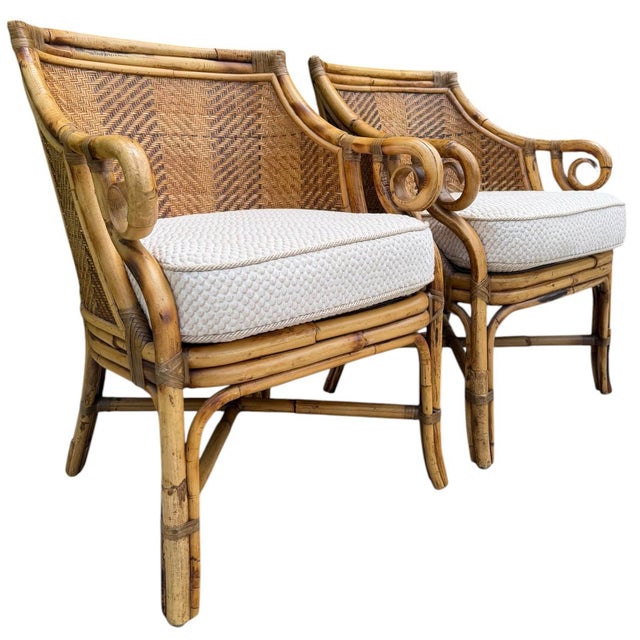A pair of Henry Link Saint Andrews scroll arm club chairs with woven rattan panels and a warm honey-toned finish. The...