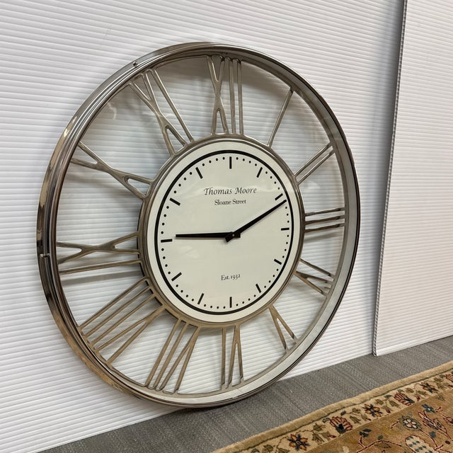 Design Plus Gallery presents a Wall Clock from Thomas Moore. The clock is mostly chrome with roman numerals going around...