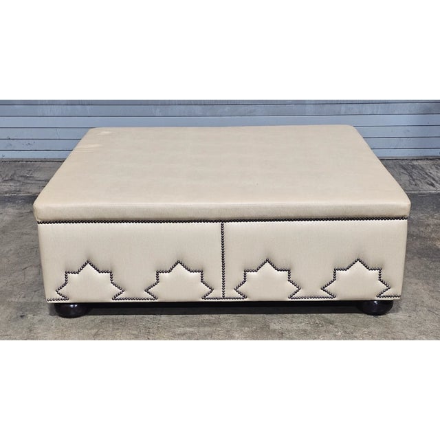 Store Item: Large Designer Beige Leather Upholstered Ottoman Pattern Tack Trim Bun Feet Description: The Ottoman features...