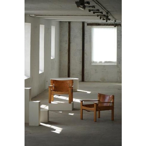 A pair of charming Swedish Mid Century Modern lounge chairs in solid pine, upholstered in leather with a fine patina....