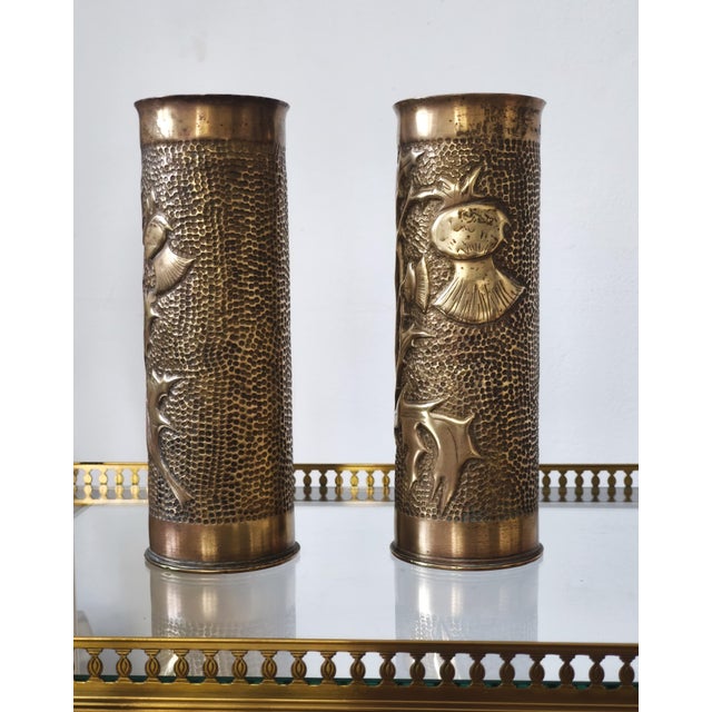 A pair of World War I trench art brass vases, decorated in relief with botanical motifs. Handcrafted, with a hammered...