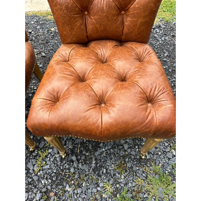Set of 4 luxurious tufted slightly distressed supple brown leather dining chairs having turned light wood legs and brass...