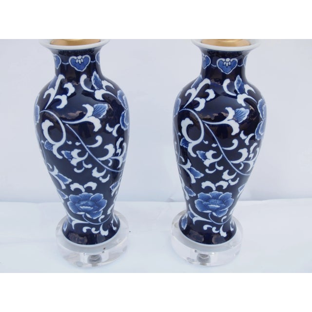Pair of Chinese Blue and White Lamps with floral design. Custom mounted on clear lucite bases.Wired and in working...