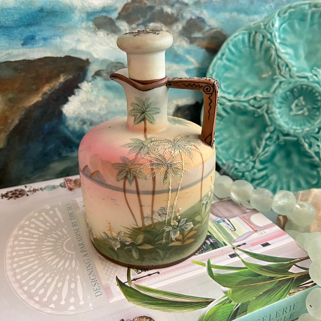 Hand painted porcelain whiskey jug by Nippon with Asian coastal scene displaying palm trees and orchids along the...