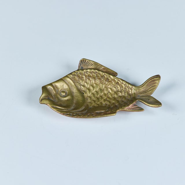 A small brass object in the shape of a fish. The center of the body dips down to form a small well with a variety of uses...