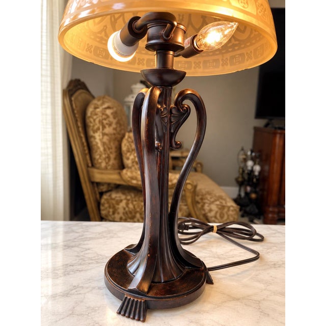 Striking vintage table lamp featuring an ornate dark bronze-tone metal base with elegant curved arms, sculptural details,...