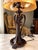 Striking vintage table lamp featuring an ornate dark bronze-tone metal base with elegant curved arms, sculptural details,...