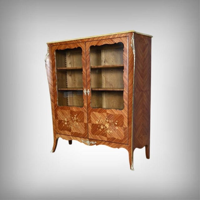 An elegant Louis XV style display cabinet with two glazed doors featuring sinuous contours, highlighting the delicate...