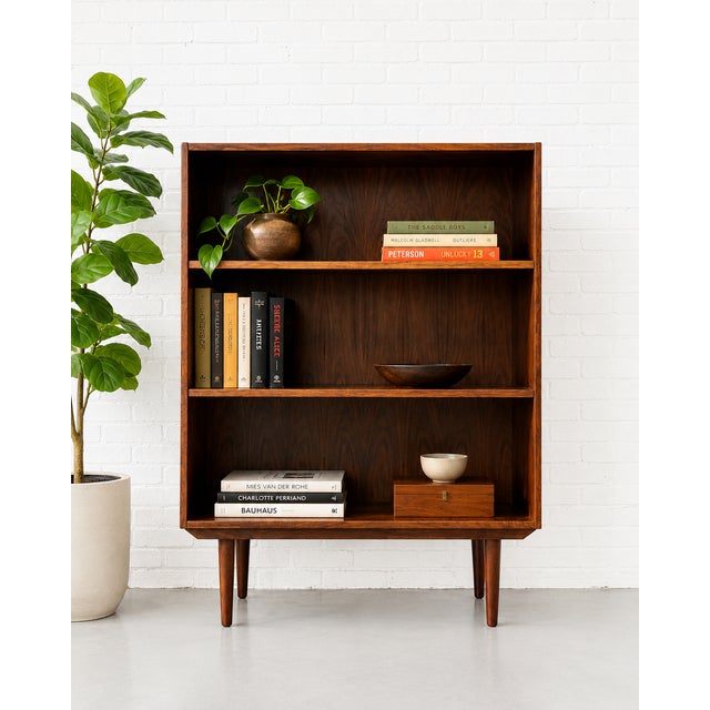 Simple + Classic Mid Century Modern ROSEWOOD bookcase, c. 1960's. This stunning piece features three wide and long...