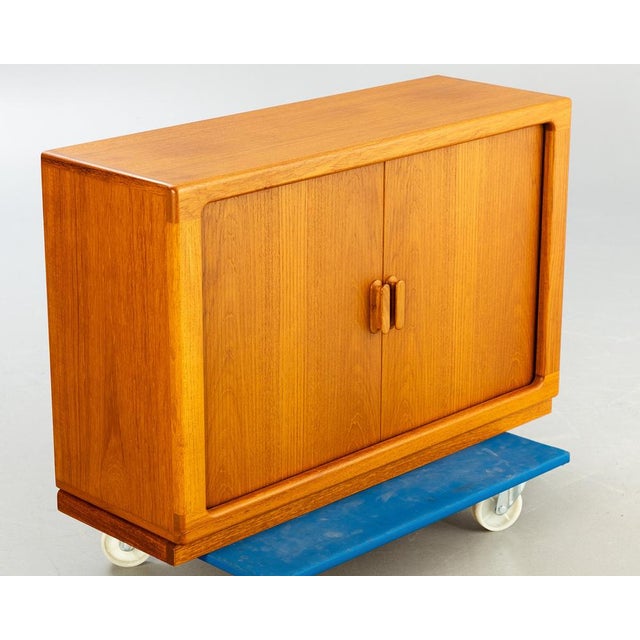 Partially veneered teak. Equipped with 2 sliding sliding doors. cca h 65 cm, w 100 cm, d 34 cm. This piece is attributed...