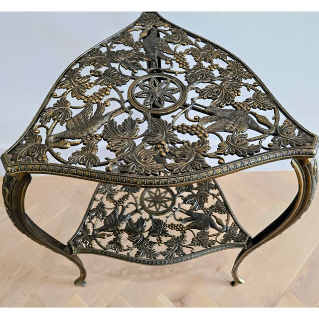 Ornate Italian Hollywood Regency brass side table featuring a rare “tous-les-trois” triangular form with two tiered...