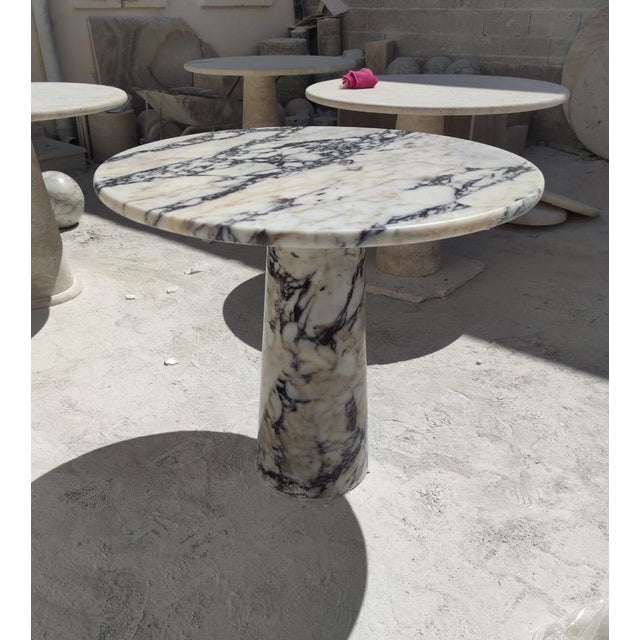 This minimalist table is crafted from Viola-veined marble, showcasing a circular tabletop that balances securely and...
