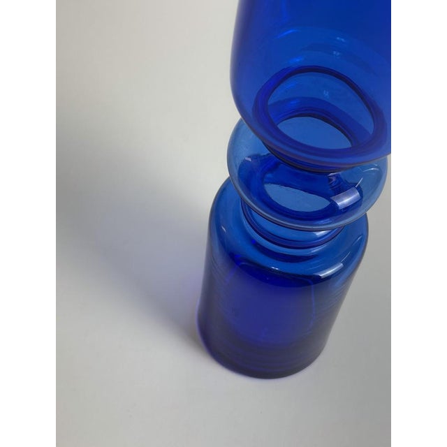 A bold 1970s cobalt blue glass vase, handcrafted in Romania, distinguished by its tall, narrow form and sculptural hooped...