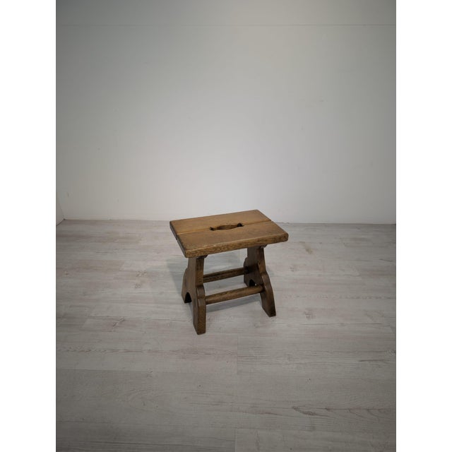 A small, rustic-style stool made of solid wood. It has a simple, sturdy construction with two side supports connected by...