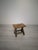 A small, rustic-style stool made of solid wood. It has a simple, sturdy construction with two side supports connected by...