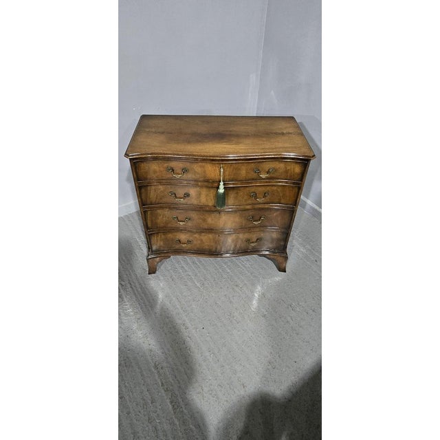 A very fine oak lined Georgian style serpentine mahogany chest of four drawers by Maples, brass swan necked handles,...
