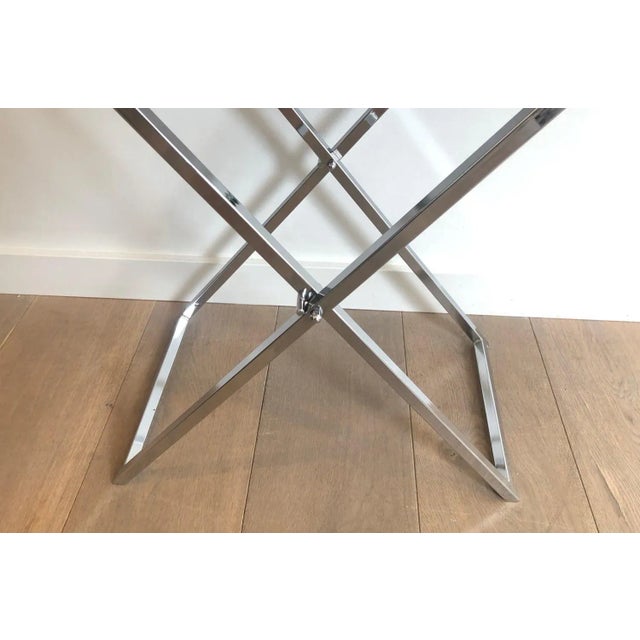 This pair of side tables is made of folding chrome bases with blueish lucite tops. This is a French work. Circa 1970.