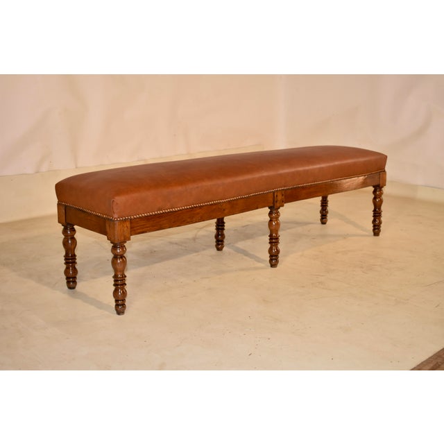 19th century English oak bench with newly upholstered leather top with nail head trim. The frame of the bench is lovely...