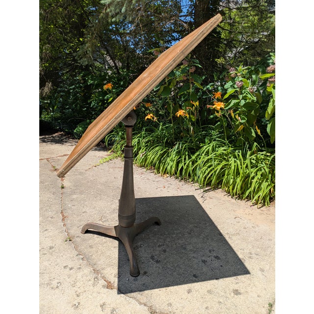 Featured here is an antique cast iron pedestal base adjustable drafting table. Once used as drafting tables these heavy...