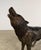 A striking and lifelike bronze sculpture of a standing wolf captured mid-howl, embodying movement, tension, and raw...