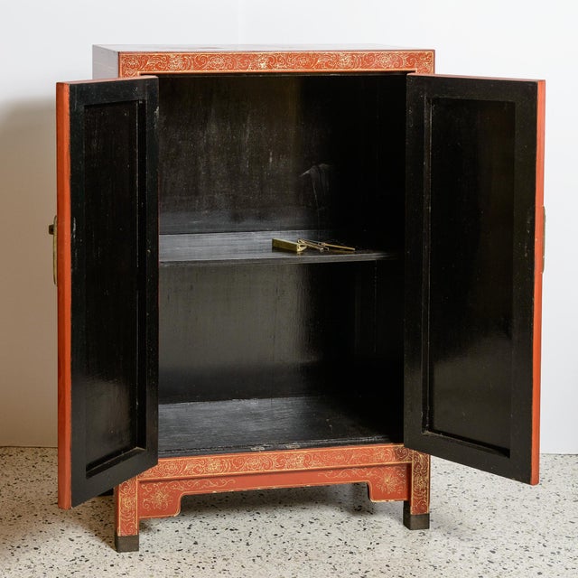 Antique, red painted Asin cabinet with two raised gold decoration and two storage shelves inside the bottom doors.