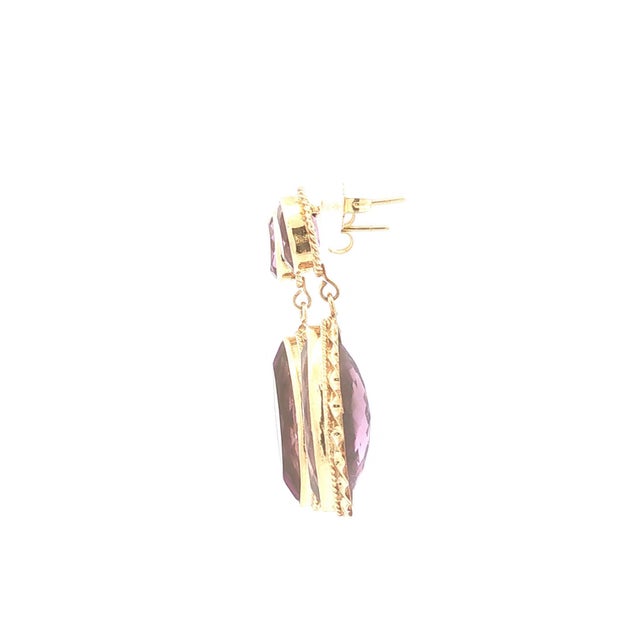 A pair of dangle earrings featuring amethyst stones. The stones are oval and marquise cut and display a rich purple hue....