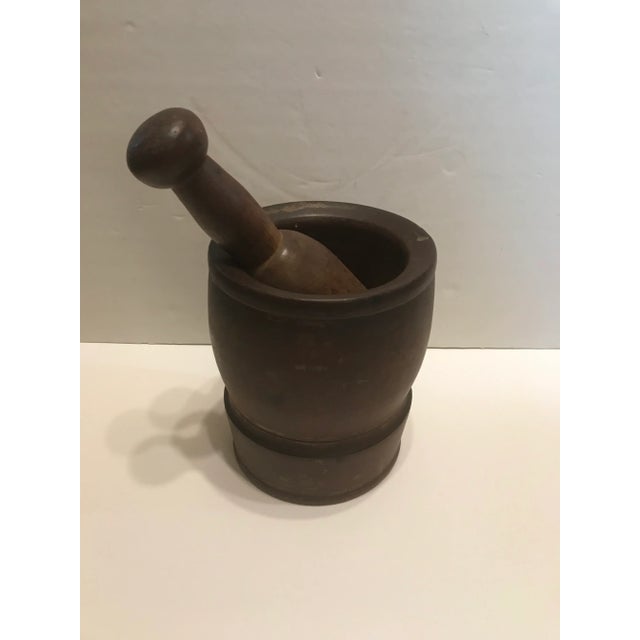 A wooden mortar and pestle, which was most likely used in a pharmacy during the later part of the 19th century. It is in a...