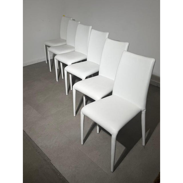 Elegant set of six Italian-design dining chairs upholstered in white leather. Featuring tall, gently curved backrests and...