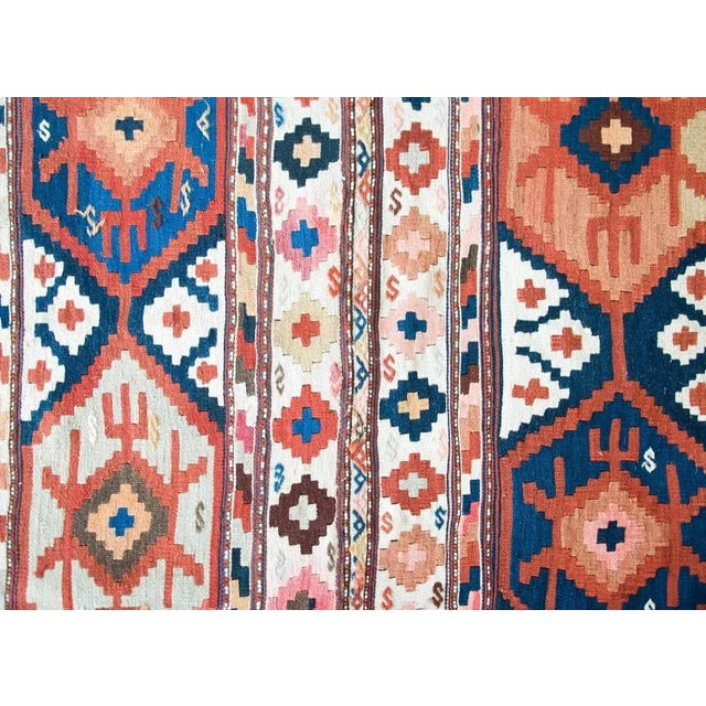 A beautiful early 20th century Persian Azari Kilim rug with four large geometric stylized flowers amidst a field of more...