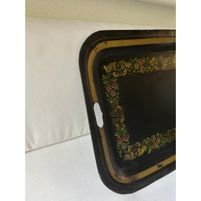 This hard working and beautiful black tole metal service tray is decorated with gold trim and gold and green flowers and...