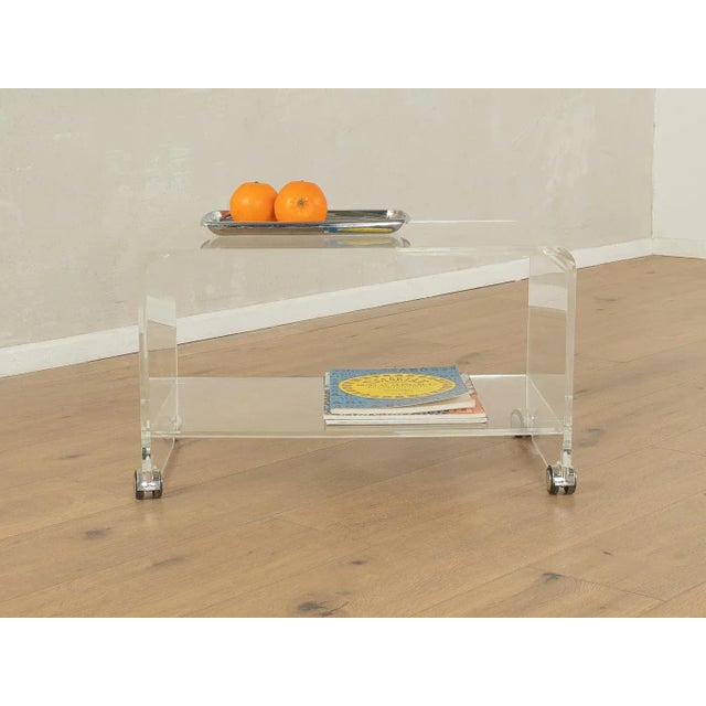 Wonderful side table from the 1960s. High-quality frame and shelves made of transparent acrylic with plastic casters....