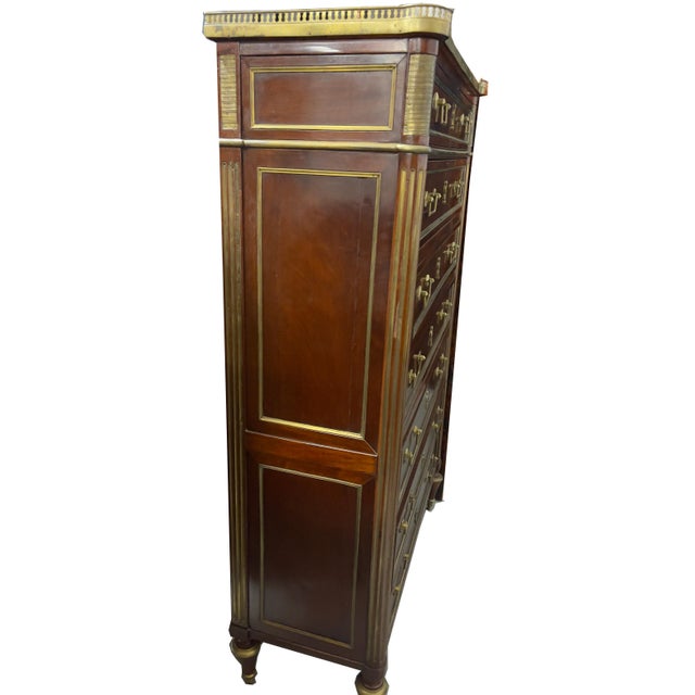 A tall handsome mahogany chest of drawers with a white marble top and bronze gallery. Bronze hardware and moldings. Turned...