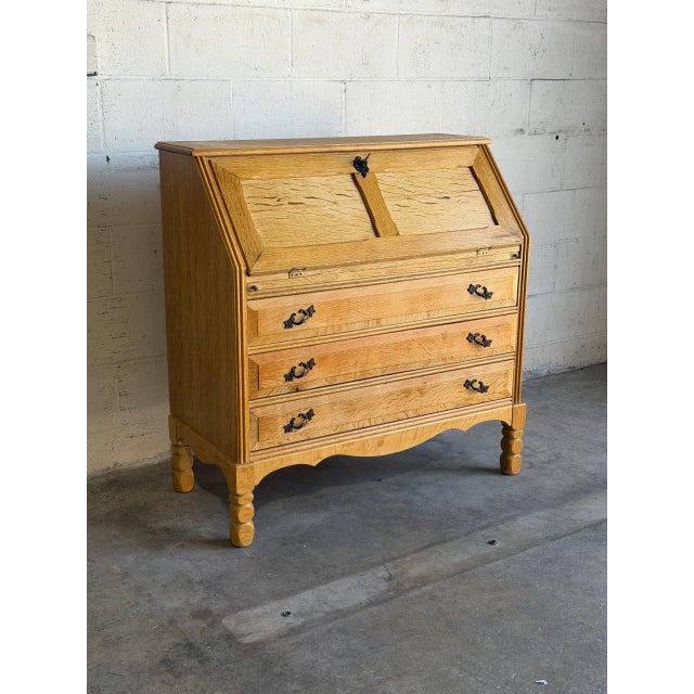 This oak secretary bureau combines a drop-front writing surface with six small interior drawers and three full-width lower...
