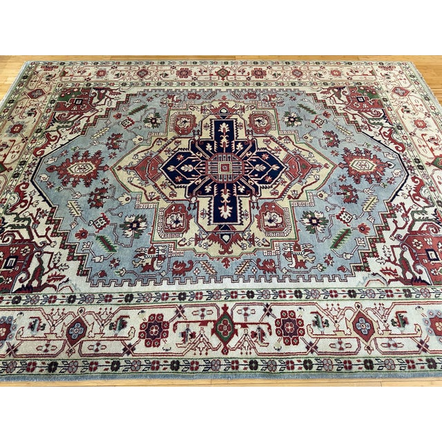 This 9'1" x 11'10" (109" x 142") handmade Indian Serapi rug features a bold medallion design on a soft gray-blue field,...