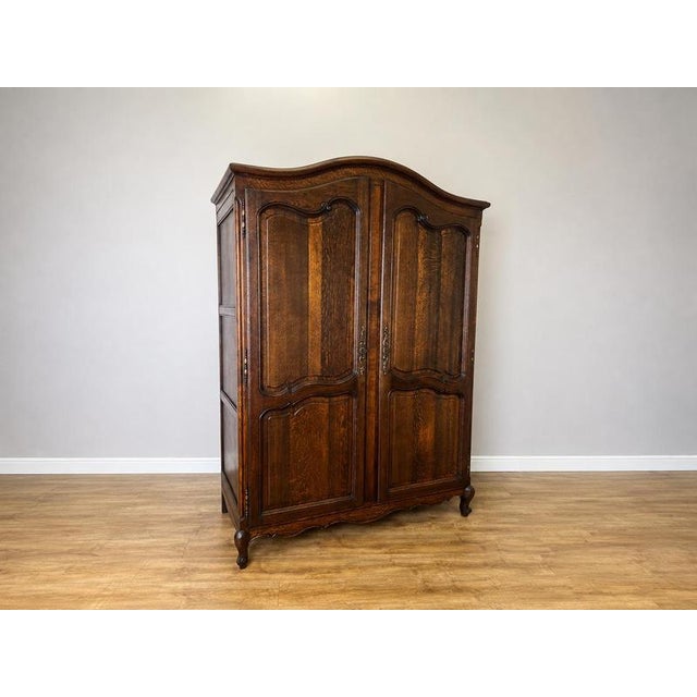 An elegant Antique French Louis wardrobe in Oak, displaying a rich dark finish, beautifully figured grain, shaped panelled...