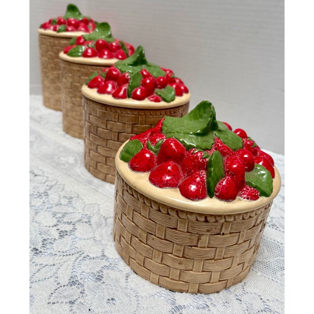 Fun set of four vintage 1970s era ceramic canisters with a basket weave pattern base and a lush deep red strawberry bushel...