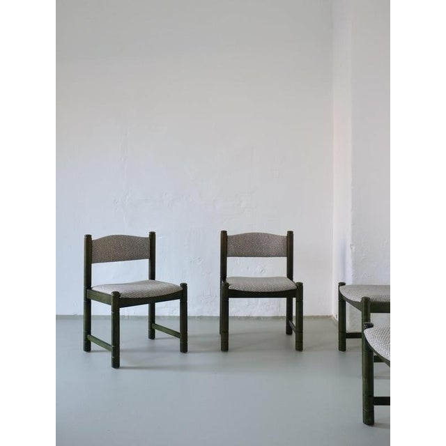 A set of four green-stained wooden chairs with grayish-blue reupholstered seats and backs. These chairs are heavy and...