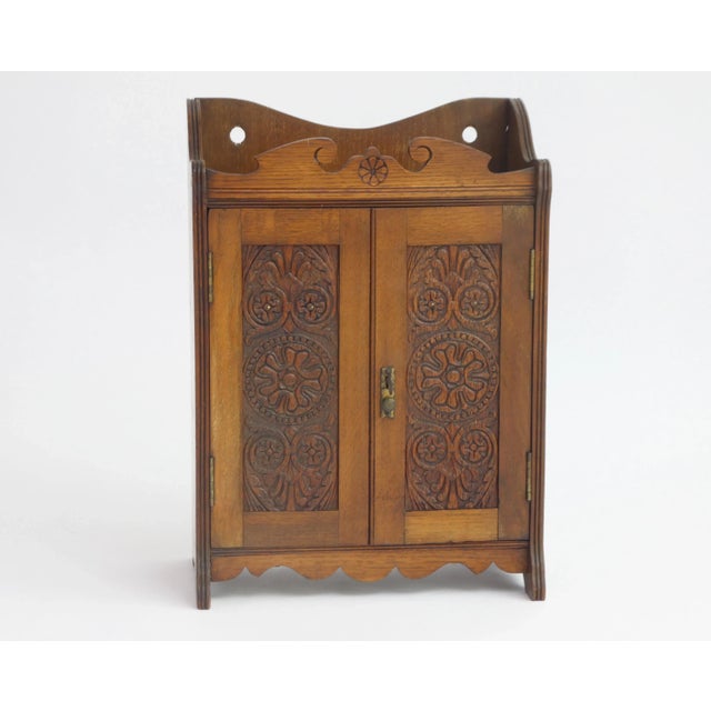 A small antique smokers cabinet with amazing hand carved floral details in the front doors. Overall the wall cabinet has...