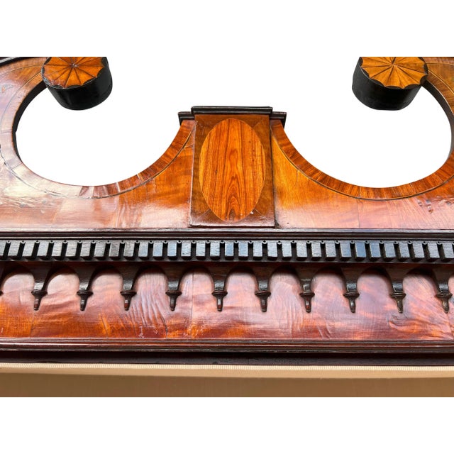 In two parts. The upper section with a broken arch cornice with inlaid pinwheels at the termination of the scrolls....