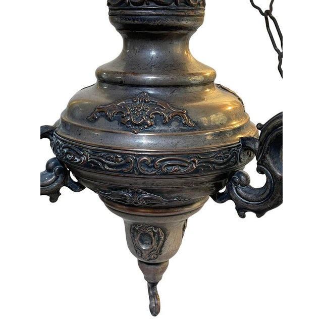 Elegant votive lamp, made of silvered and embossed copper, adapted with electrical connection. A glass flame lamp cover...