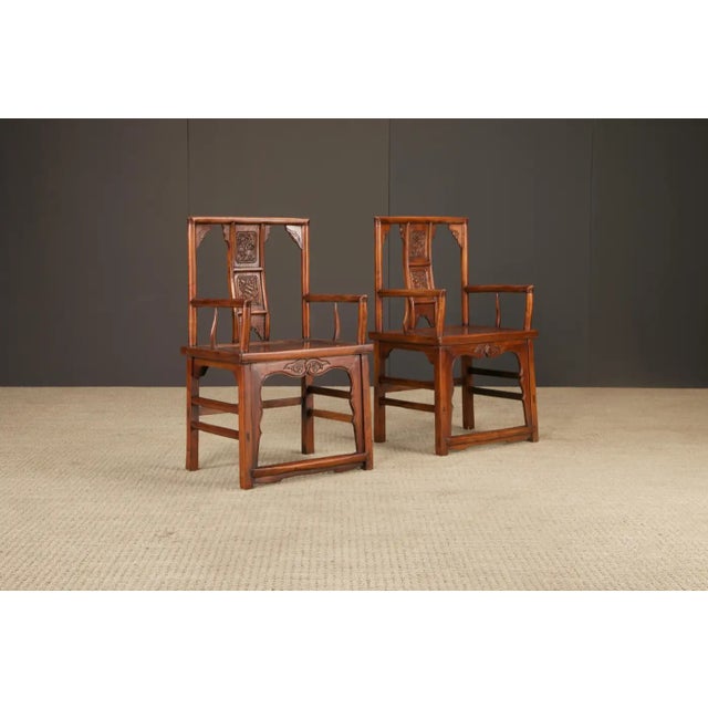 A refined pair of Chinese armchairs, crafted in solid elmwood and likely dating to the Qing Dynasty period (1644–1912),...