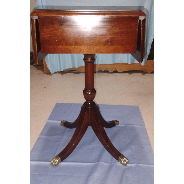 This authentic Duncan Phyfe style mahogany drop-leaf pedestal side table was manufactured by the renowned Brandt Furniture...