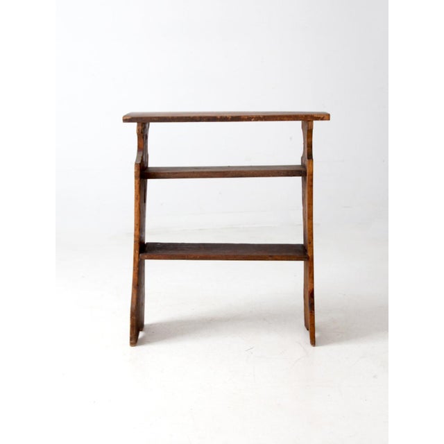 This antique handmade pine shelf features sculpted side panels, visible shaping marks, and a warm, aged finish. Its three-...