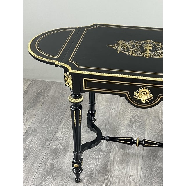 A superb Napoleon III style coffee table in black lacquered wood, richly decorated with gilt lines and motifs in the...