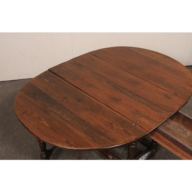 A Swedish fir wood double drop leaf and gate-leg table table from the 18th century. This antique oval-shaped table from...