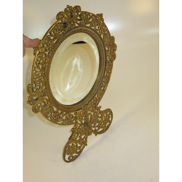 This product is a beveled glass mirror with a gold gilt metal frame. Victorian for use on a table or wall. The mirror is...