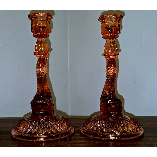 Bring a touch of 1930s elegance to your mantel or tablescape with this charming pair of pink Depression glass dolphin...