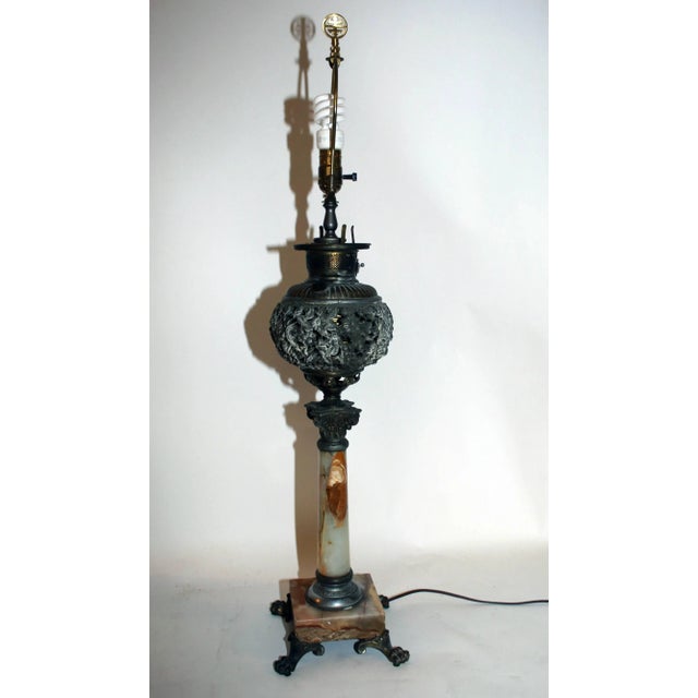 Antique oil burning lamp converted to electricity. Features include reticulated bronze ormolu in a floral pattern with an...