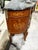 This demi lune commode decorated with floral marquetry and bronze ormolu has a black marble top. The form of the commode...