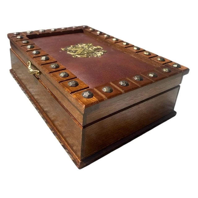 Beautiful vintage wooden jewelry box featuring a studded leather top and ornate crest. Good condition after careful...
